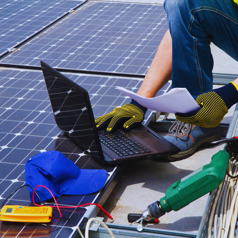 Technicien travaillant sur des panneaux solaires avec un ordinateur portable.